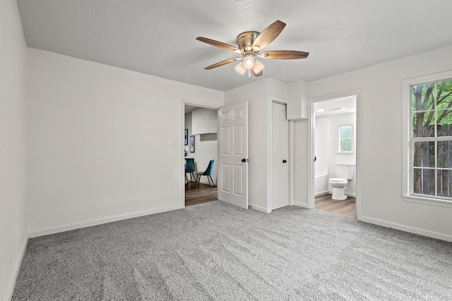 unfurnished bedroom featuring ceiling fan, baseboards, carpet flooring, and ensuite bathroom