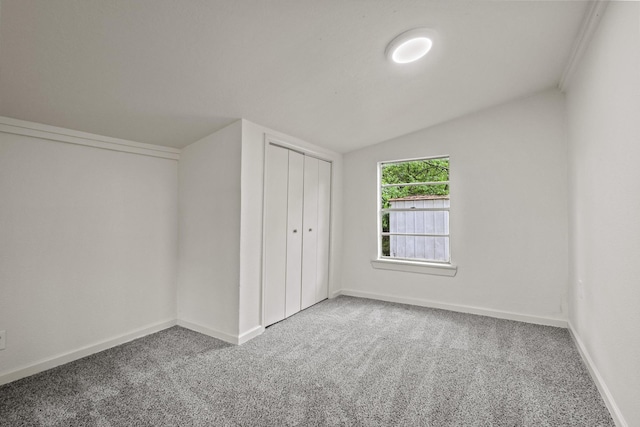 unfurnished bedroom with vaulted ceiling, carpet flooring, and baseboards