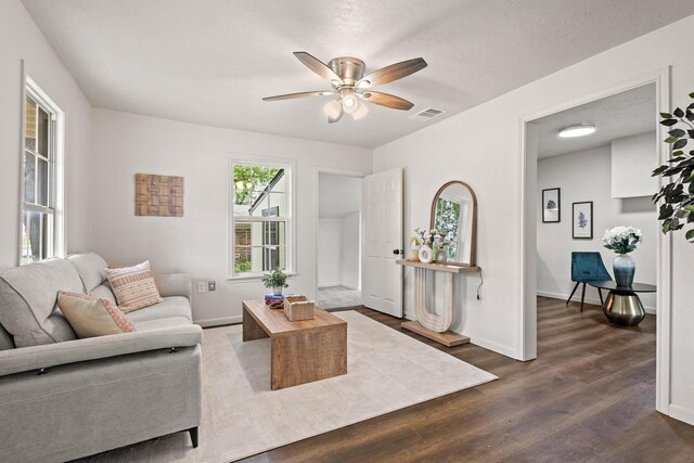 living room featuring baseboards, visible vents, a ceiling fan, and dark wood-style floors