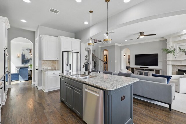 kitchen with visible vents, arched walkways, appliances with stainless steel finishes, a sink, and white cabinets