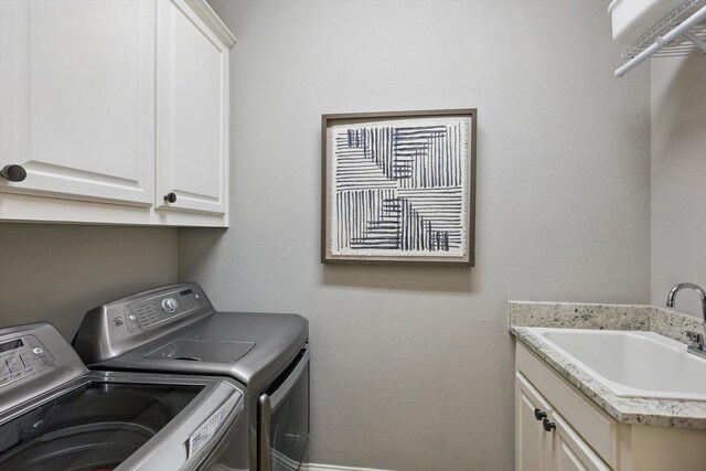 washroom featuring a sink, cabinet space, and washing machine and clothes dryer