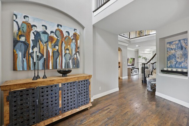 foyer entrance featuring arched walkways, baseboards, wood finished floors, and stairway