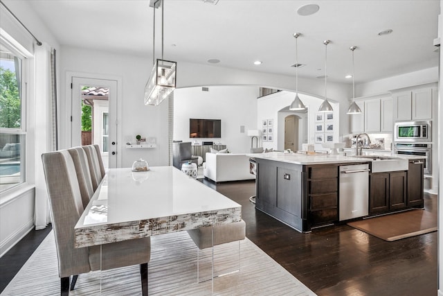 13508 Balint Ln, Frisco, TX 75035 - kitchen with dark wood finished floors, stainless steel appliances, a sink, arched walkways, and a spacious island