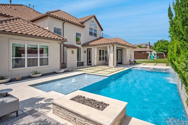 13508 Balint Ln, Frisco, TX 75035 - back of house with a fire pit, fence, a patio, a fenced in pool, and stucco siding