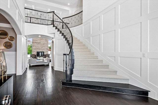 13508 Balint Ln, Frisco, TX 75035 - stairway featuring a towering ceiling, wood finished floors, arched walkways, baseboards, and a tiled fireplace