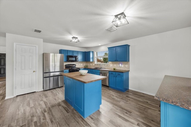 5712 Goldfinch Way, Dallas, TX 75249 - kitchen with a sink, blue cabinetry, wood counters, visible vents, and black appliances