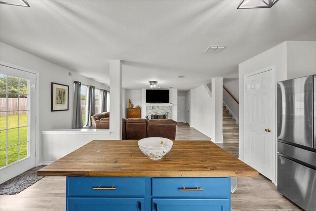 5712 Goldfinch Way, Dallas, TX 75249 - kitchen with freestanding refrigerator, a fireplace, wooden counters, and blue cabinetry