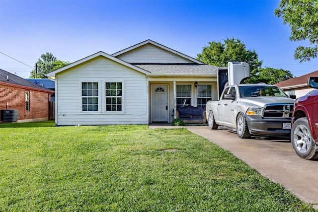 view of front of home featuring a shingled roof, a front yard, and central AC unit