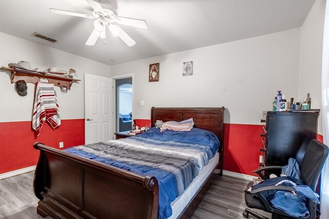 bedroom featuring baseboards, a ceiling fan, wood finished floors, and visible vents