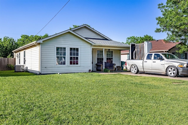 view of front facade with covered porch, central AC, a front yard, and fence