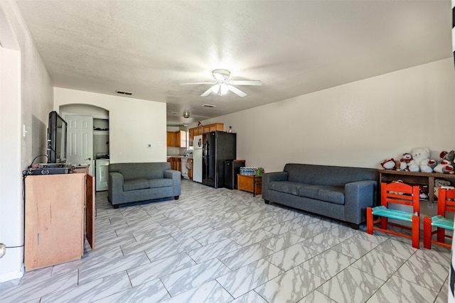 living room with a ceiling fan, visible vents, arched walkways, and marble finish floor