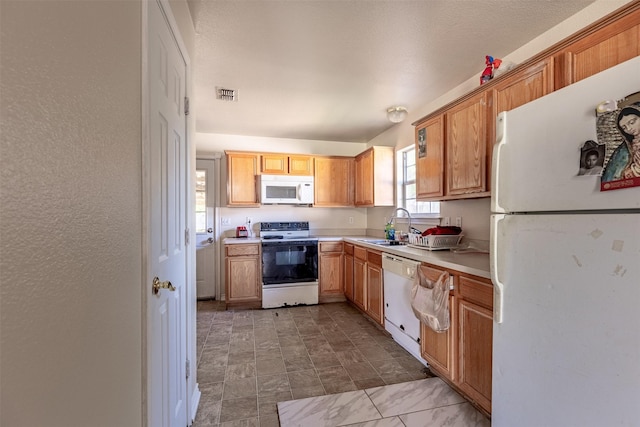 kitchen with visible vents, light countertops, white appliances, and a sink