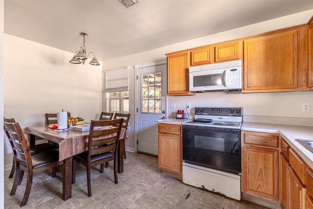 kitchen featuring light countertops, range with electric cooktop, a notable chandelier, and white microwave