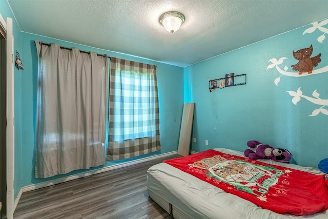 bedroom featuring wood finished floors and a textured ceiling