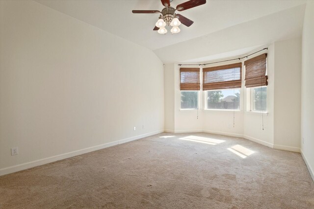 spare room with vaulted ceiling, carpet flooring, baseboards, and a ceiling fan
