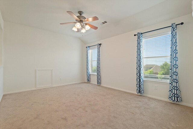 carpeted empty room featuring a ceiling fan, visible vents, a wealth of natural light, and vaulted ceiling