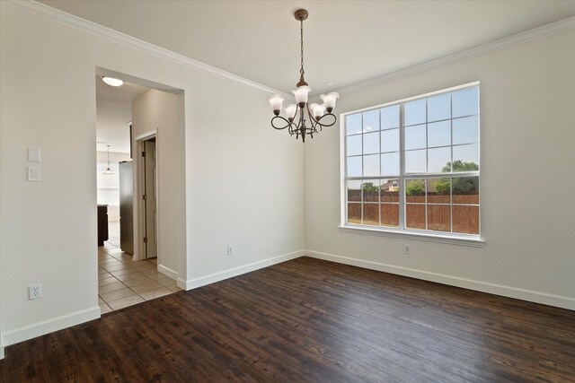 unfurnished room with ornamental molding, baseboards, a notable chandelier, and wood finished floors