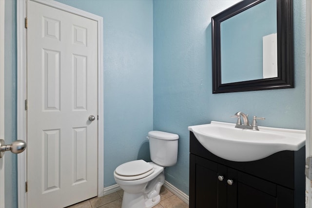 half bathroom featuring baseboards, tile patterned floors, vanity, and toilet