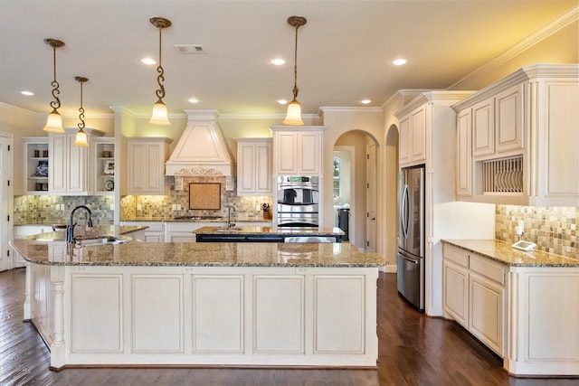 kitchen with stainless steel appliances, a large island, visible vents, a sink, and custom range hood