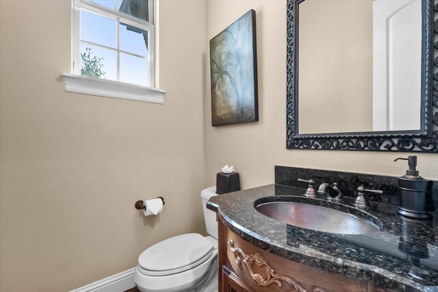 bathroom featuring baseboards, vanity, and toilet