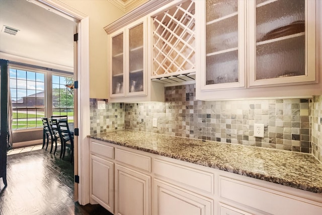 kitchen with visible vents, cream cabinetry, light stone counters, and tasteful backsplash