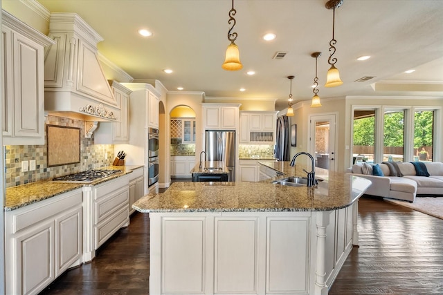 kitchen with a sink, a large island, stainless steel appliances, ornamental molding, and visible vents