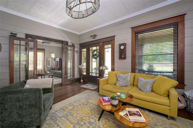 living room featuring an ornate ceiling, wood finished floors, french doors, wood walls, and ornamental molding