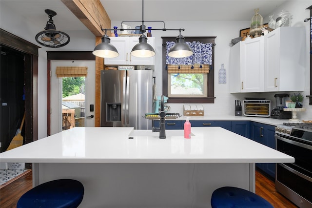 kitchen with stainless steel appliances, a toaster, white cabinetry, blue cabinetry, and light countertops