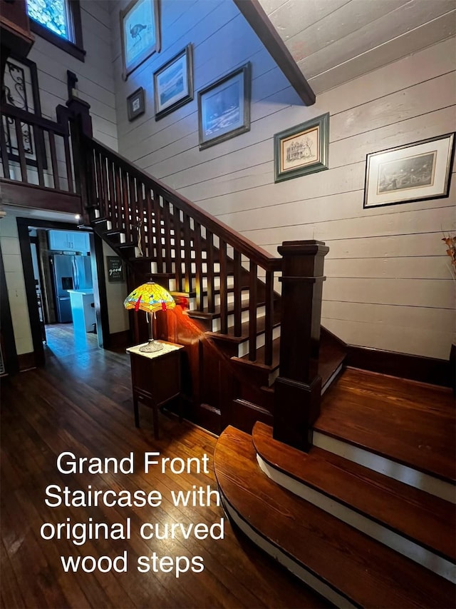 staircase with wooden walls and wood finished floors