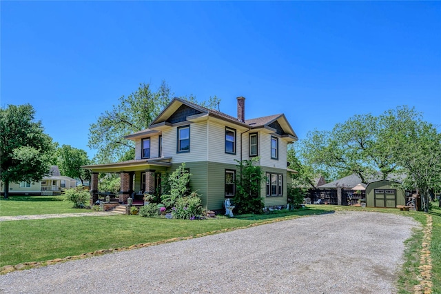 view of front of house featuring a storage shed, an outbuilding, a front lawn, a chimney, and covered porch