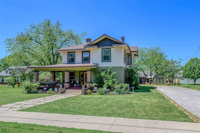 victorian home featuring a shed, a chimney, a front lawn, covered porch, and an outbuilding