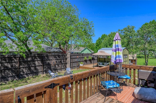 wooden deck with a fenced backyard, an outbuilding, and outdoor dining area