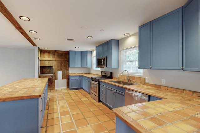 kitchen featuring blue cabinetry, recessed lighting, stainless steel appliances, and a sink
