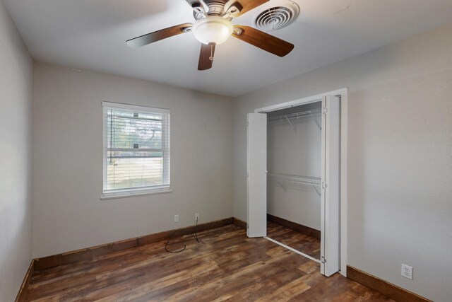 unfurnished bedroom featuring dark wood-style floors, visible vents, a ceiling fan, a closet, and baseboards