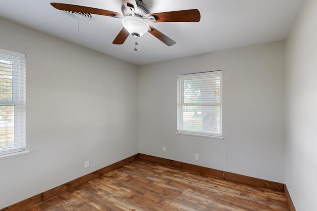 empty room with baseboards, a ceiling fan, wood finished floors, and a wealth of natural light