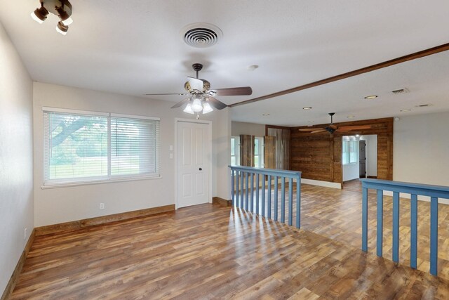 spare room featuring wood finished floors, baseboards, a ceiling fan, and visible vents