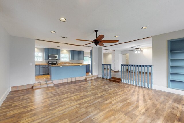 unfurnished living room with recessed lighting, light wood finished floors, a ceiling fan, baseboards, and built in features