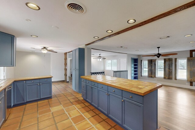 kitchen featuring blue cabinets, visible vents, open floor plan, and ceiling fan