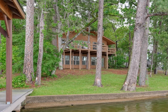 back of property featuring a deck with water view and a lawn