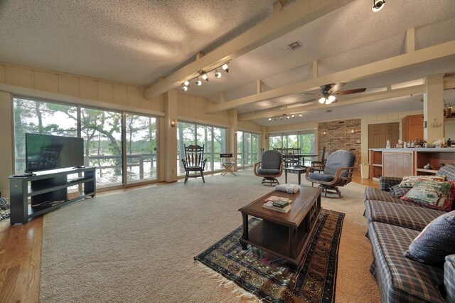 living area featuring lofted ceiling with beams, a textured ceiling, visible vents, ceiling fan, and rail lighting