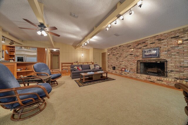 carpeted living area with visible vents, vaulted ceiling with beams, a ceiling fan, a fireplace, and a textured ceiling