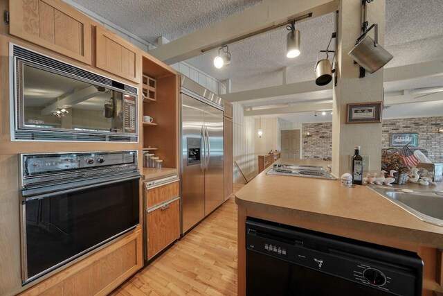 kitchen featuring open shelves, a sink, a textured ceiling, black appliances, and light wood-style flooring