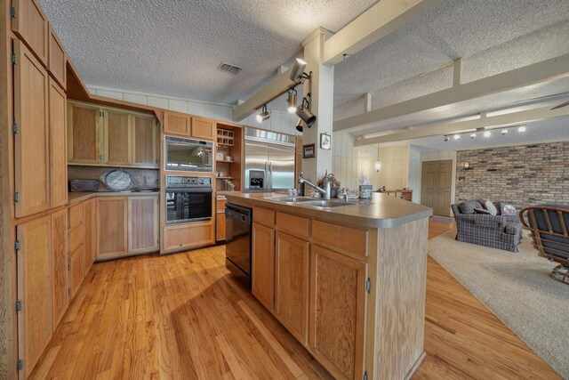 kitchen featuring a sink, light wood-type flooring, open floor plan, visible vents, and black appliances
