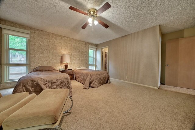 carpeted bedroom with ceiling fan, baseboards, and a textured ceiling