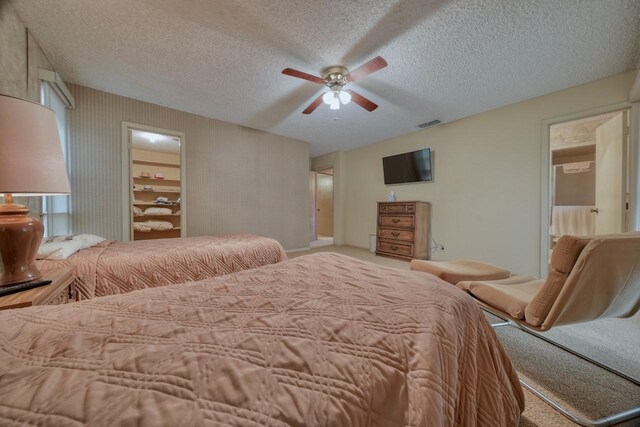 carpeted bedroom with a textured ceiling, ceiling fan, and visible vents