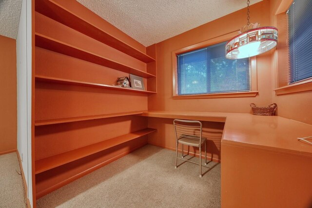 office area with carpet floors, built in study area, and a textured ceiling