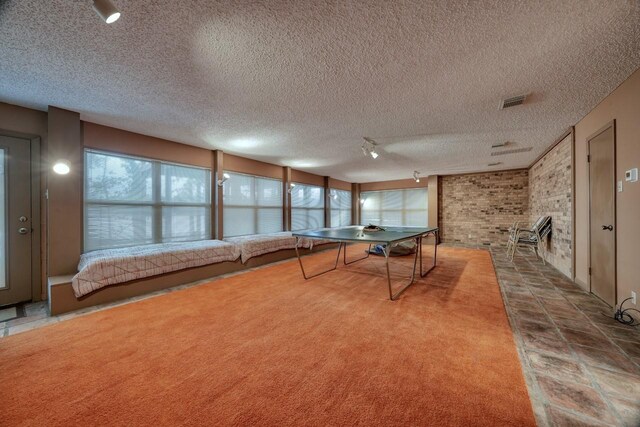 playroom featuring brick wall, a textured ceiling, and visible vents