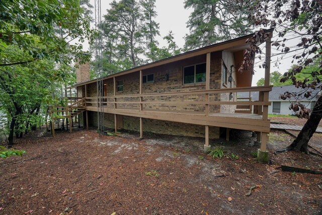 rear view of property with a chimney, a deck, and stairs
