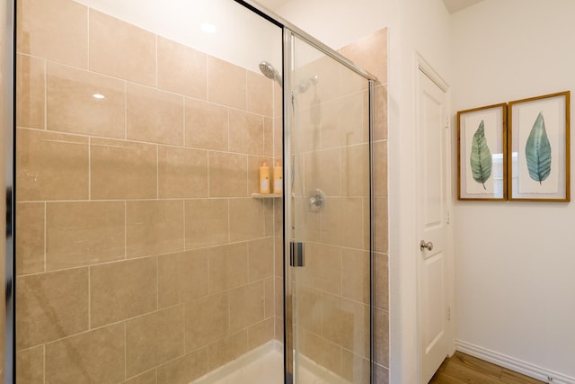 full bathroom featuring baseboards, wood finished floors, and a stall shower