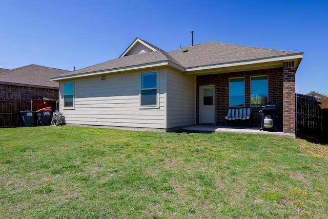 rear view of house featuring a lawn, fence, a patio, and brick siding